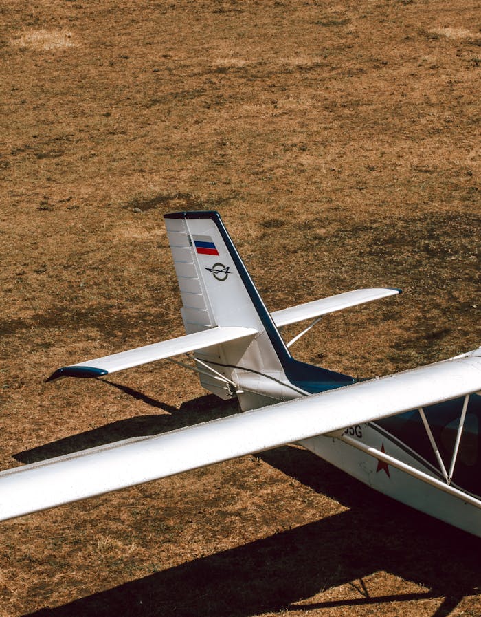 A small airplanes tail and wing on a field, viewed from above, showcasing aviation design.